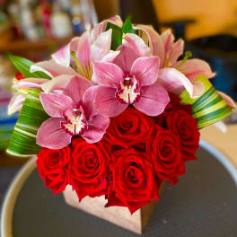 Bouquet of red roses and pink orchids with green leaf accents
