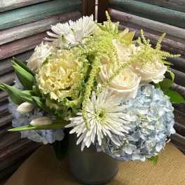 White roses, blue hydrangeas, and white daisies in a vase