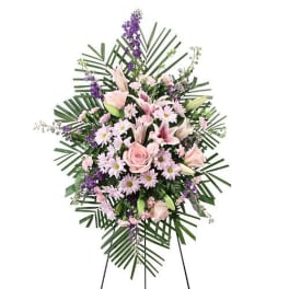 Standing spray of pink lilies, roses, and purple flowers on a white background