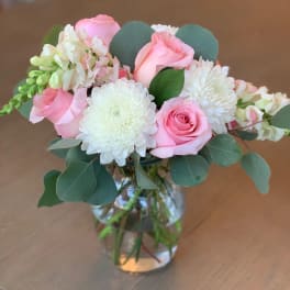 Pink roses and white mums in a glass vase with eucalyptus