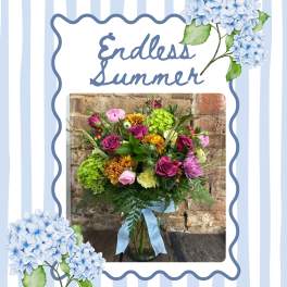 Mixed bouquet in a glass vase with blue ribbon and hydrangea accents