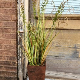 Tall potted arrangement of ornamental grasses in a copper planter