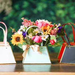 Three small handled gift boxes, one filled with mixed flowers