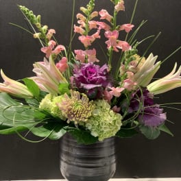 Mixed floral arrangement in a dark vase with pink snapdragons and lilies
