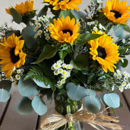 Bouquet of sunflowers and small white daisies in a glass vase
