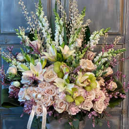 Large floral arrangement with pale roses, lilies, and orchids in a pedestal vase