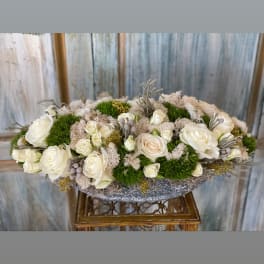 Low oval arrangement of white roses with green moss accents