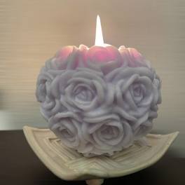 Rose-shaped candle in a shallow ceramic dish
