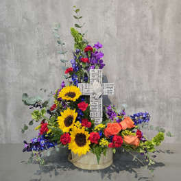 Tall floral arrangement with sunflowers, roses, and purple blooms in a round basket