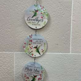 Three hanging round plaques with hummingbirds and floral designs on a wall.