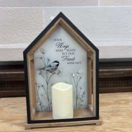 House-shaped memorial lantern with a candle and bird illustration
