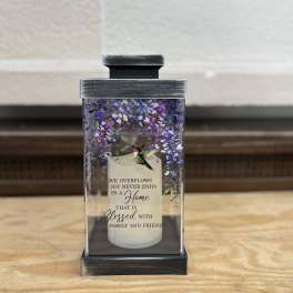 Decorative candle in a glass lantern with purple floral accents