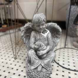 Gray angel statue holding a small dog figurine