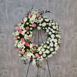 Large floral wreath with pink and white flowers on a black stand