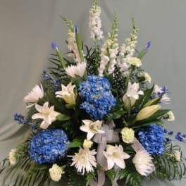 Blue hydrangeas and white lilies in a tall floral arrangement