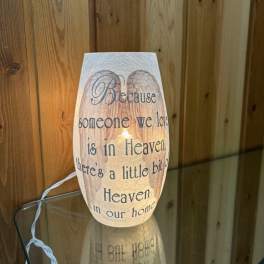 Lit memorial candle with sympathy text on a glass holder
