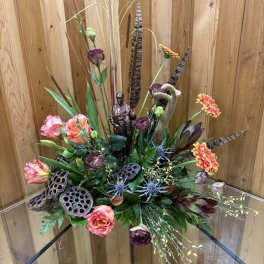 Mixed floral arrangement with orange and purple blooms in a glass vase
