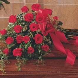 Bouquet of red roses with a red ribbon on a wooden surface