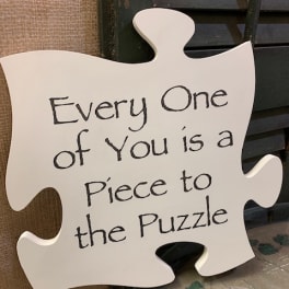 White puzzle-piece sign with handwritten text