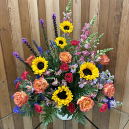 Mixed bouquet with sunflowers, roses, and snapdragons in a white vase