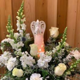 White floral arrangement with an angel figurine in the center