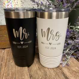 Two engraved tumblers labeled Mr. and Mrs. beside purple flowers.