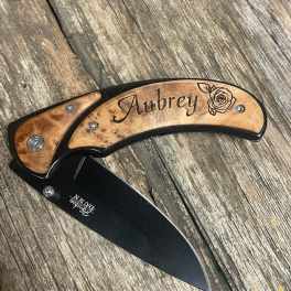 Engraved folding knife with a wooden handle and black blade