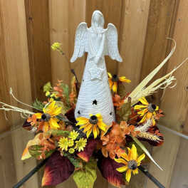 Angel figurine surrounded by yellow and orange flowers in an autumn arrangement