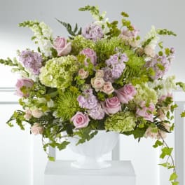 Large pastel floral arrangement in a white urn vase
