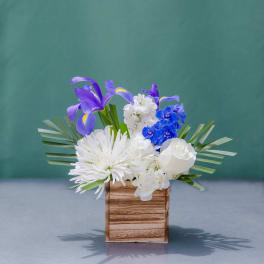 White and blue floral arrangement in a wooden box