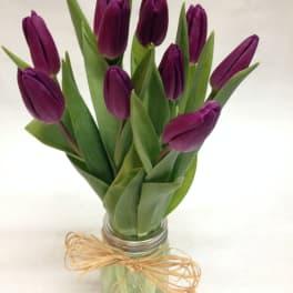 Purple tulips in a glass jar tied with raffia