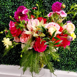 Mixed bouquet of pink and red flowers in a clear glass vase