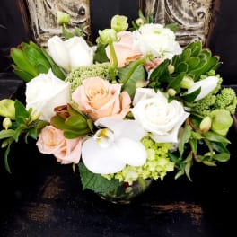 Bouquet of white and peach roses with white orchids in a glass vase
