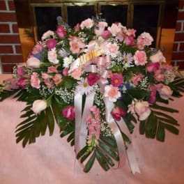 Pink and white floral arrangement with ribbon on a table
