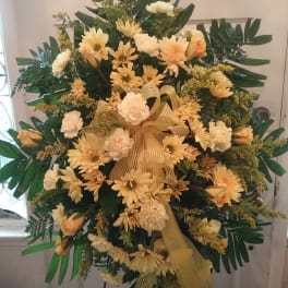 Large yellow and white funeral spray with ribbon on an easel