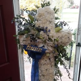 White funeral standing spray with lilies and blue ribbon on an easel
