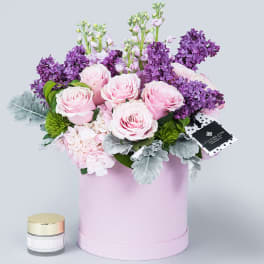 Pink roses and purple lilacs in a pastel pink hat box