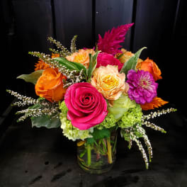 Bright mixed bouquet of roses and zinnias in a glass vase