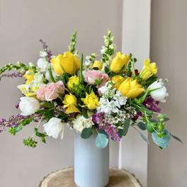 Yellow and pink roses in a light blue vase with white blooms