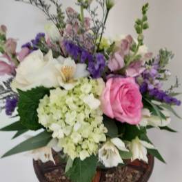 Mixed arrangement with pink rose, white blooms, and green hydrangea in a glass vase