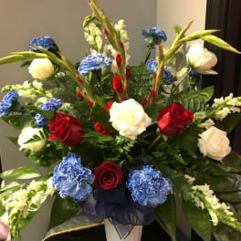 Red, white, and blue floral arrangement in a white pedestal vase