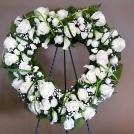 White floral wreath on a stand with roses and calla lilies