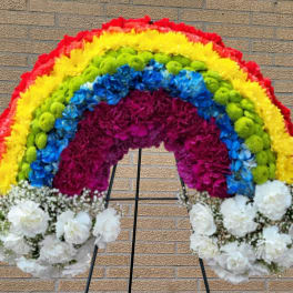 Rainbow floral standing spray on an easel with white flowers at the base