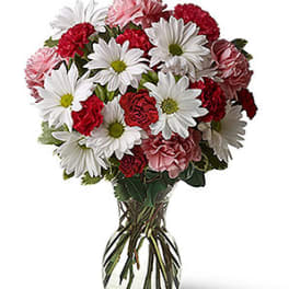 Bouquet of white daisies and red carnations in a glass vase