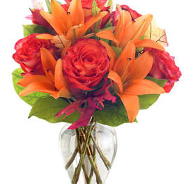 Bouquet of orange lilies and red roses in a clear glass vase
