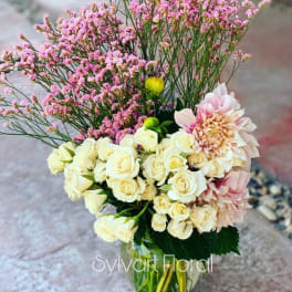Bouquet of cream roses and pink blooms in a glass vase