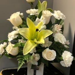 White roses and a yellow lily in a vase arrangement