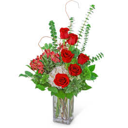 Red roses and pink flowers in a clear glass vase