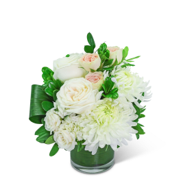 White roses and chrysanthemums in a glass vase with green leaves