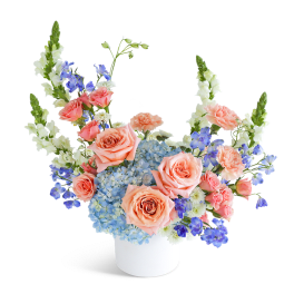 Peach roses and blue hydrangeas in a white vase